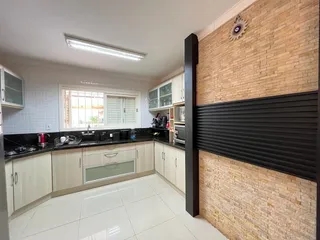 Foto interna de uma cozinha com armários brancos e piso claro.