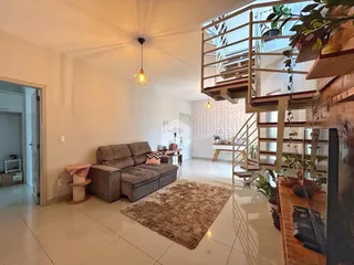 Sala de estar ampla com piso claro e escadaria de madeira visível.