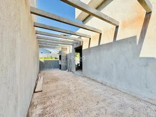 Corredor interno de uma estrutura de concreto com vigas expostas.
