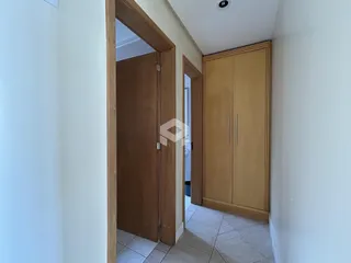 Hall de entrada com porta de madeira e armário em um apartamento.
