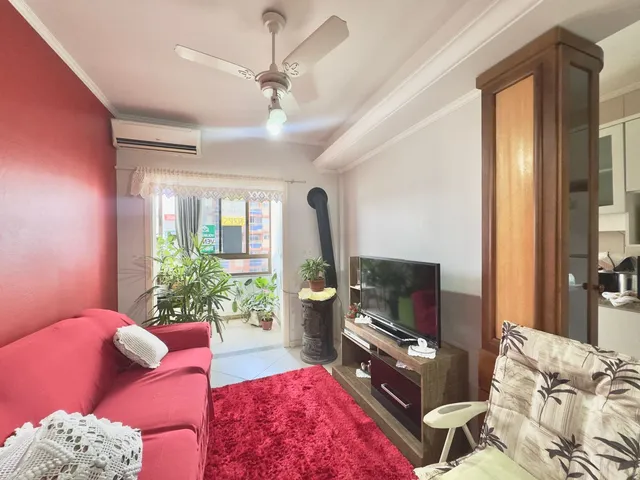 Sala de estar com sofá vermelho e televisão em ambiente interno.