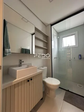 Foto interna de um banheiro moderno com box de vidro.