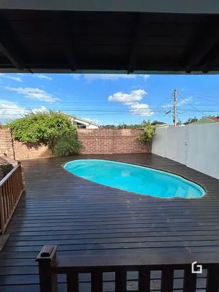 Foto de uma piscina com deck de madeira em uma propriedade.