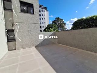 Vista de uma área externa com piso de concreto adjacente a um prédio residencial.