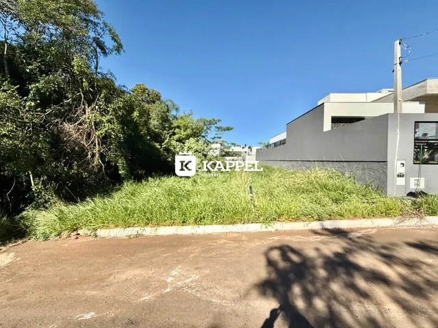 Foto da fachada de um edifício moderno em Lajeado, Brasil, com vegetação alta na frente.