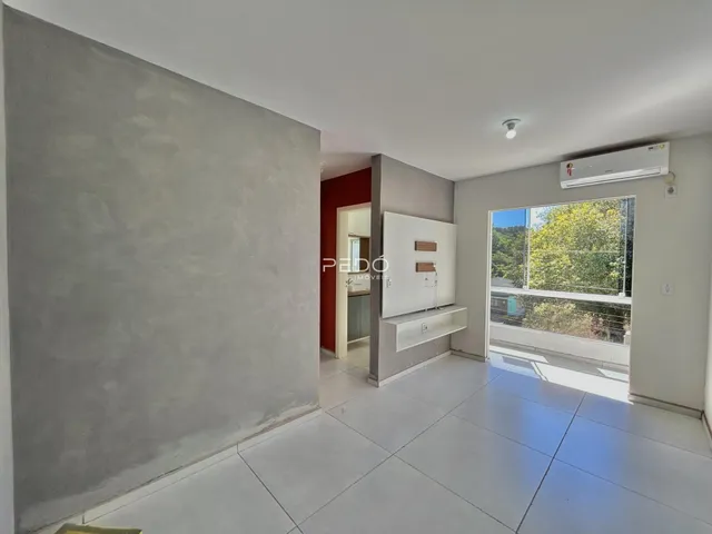 Vista interna de uma sala com parede cinza e porta vermelha.