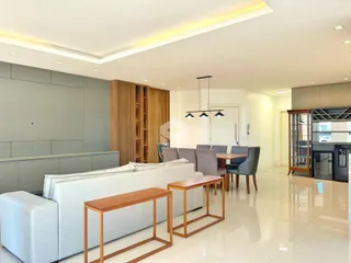 Sala de estar moderna com sofá e móveis de madeira em um apartamento.