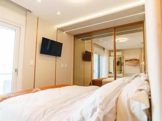 Quarto com cama grande e portas de vidro que dão acesso a outra área.