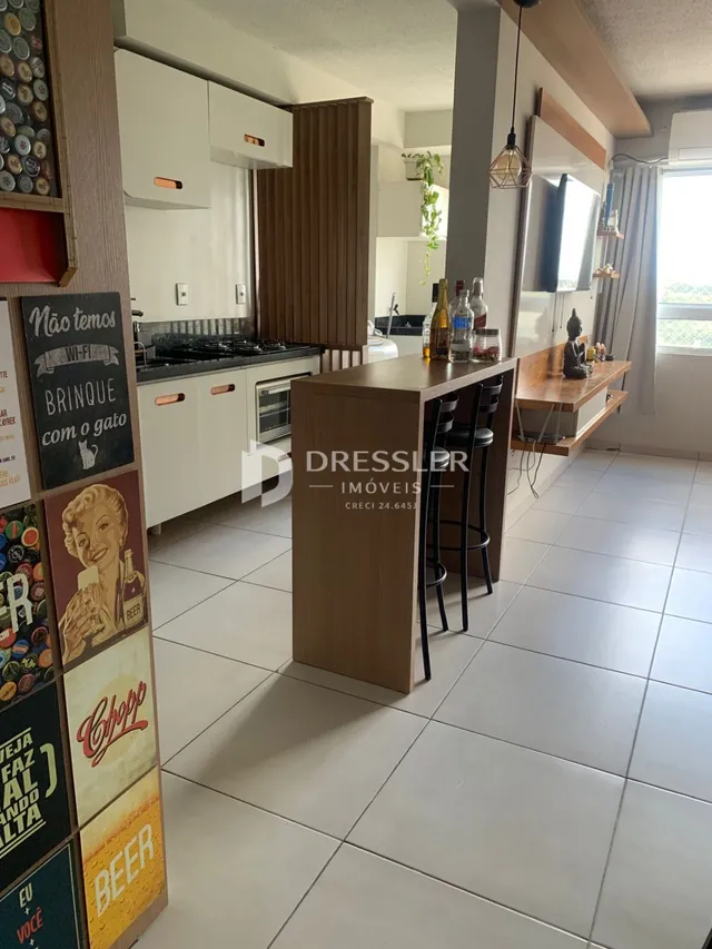 Interior de uma sala de estar com cozinha e área de jantar em um imóvel.