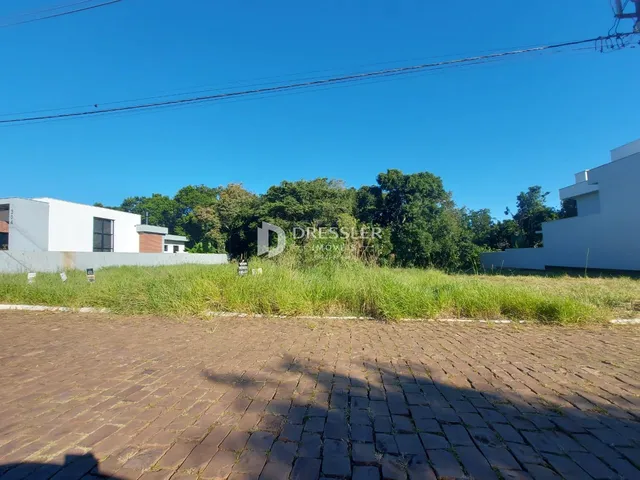 Vista externa de uma propriedade com gramado e área pavimentada.