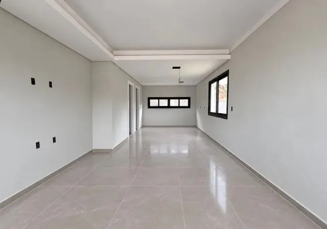 Corredor longo com piso de porcelanato claro e paredes brancas.