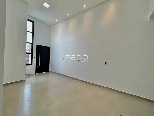 Vista interna de um corredor com paredes brancas e piso de cerâmica.