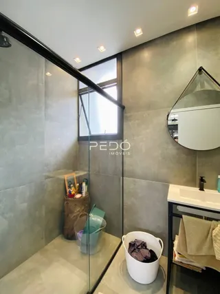 Vista parcial de um ambiente interno com divisórias de vidro e revestimento de parede em tom de cinza.