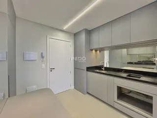 Imagem de um ambiente interno moderno com armários cinzas e bancadas escuras.