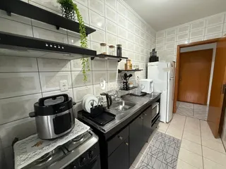 A cozinha apresenta armários escuros e revestimento de azulejos brancos.
