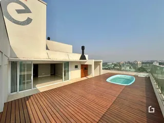 Vista de uma área externa com deck de madeira e piscina no topo de um imóvel.