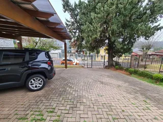 Área externa pavimentada com tijolos e vegetação ao fundo.
