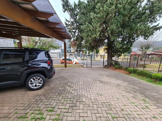 Área externa pavimentada com tijolos e vegetação ao fundo.