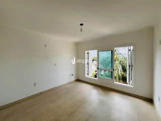 Sala de estar com piso de madeira clara e grande janela voltada para o exterior.
