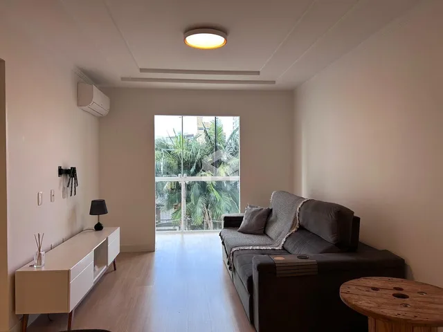 Sala de estar com piso de madeira e vista para o exterior.