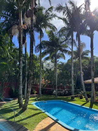 Piscina azul cercada por gramado e palmeiras em uma área externa.
