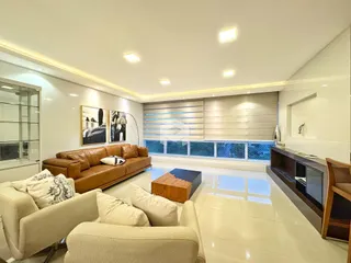 Sala de estar ampla com sofá de couro marrom e piso claro.