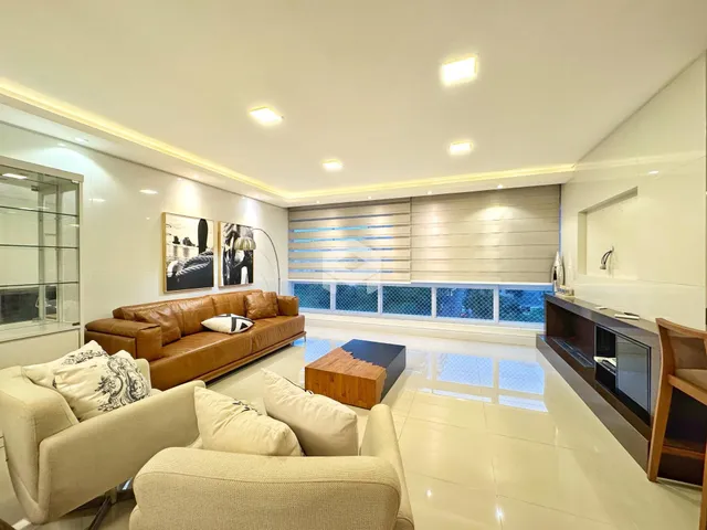 Sala de estar ampla com sofá de couro marrom e piso claro.