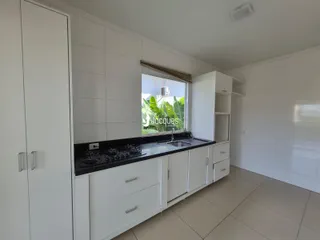 Vista interna de uma cozinha com armários brancos e piso claro.