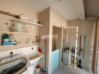 Interior de uma área de serviço com bancada e armários brancos.