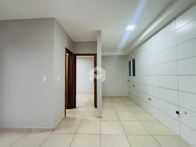 Corredor interno de uma residência com paredes brancas e piso claro.