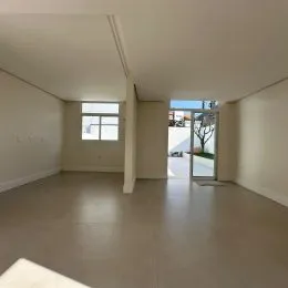 Sala de estar ampla com piso liso e paredes brancas.