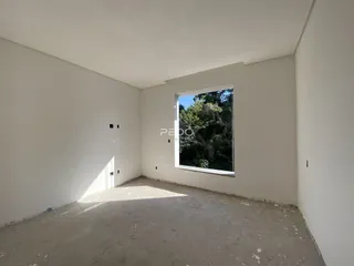 Ambiente interno de uma sala vazia com paredes brancas e piso de concreto.