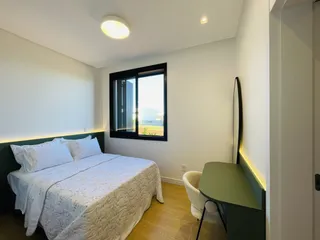 Quarto com cama e janela de grande porte.