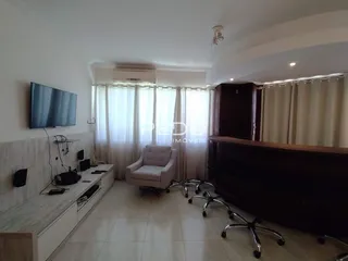 Sala de estar com cortinas e televisão montada na parede.