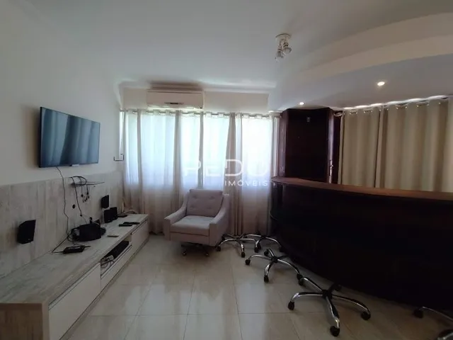 Sala de estar com cortinas e televisão montada na parede.