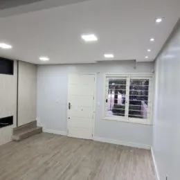 Ambiente interno com piso claro e iluminação embutida em uma sala.