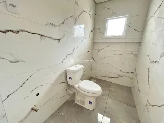 Foto de um banheiro com revestimento de parede em mármore e um vaso sanitário branco.