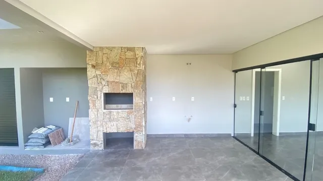 Sala ampla com lareira de pedra e piso de porcelanato.