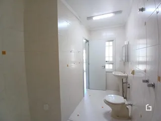 Foto de um banheiro com revestimento branco e piso claro.