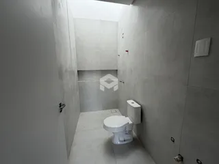 Corredor interno com paredes brancas e vaso sanitário.