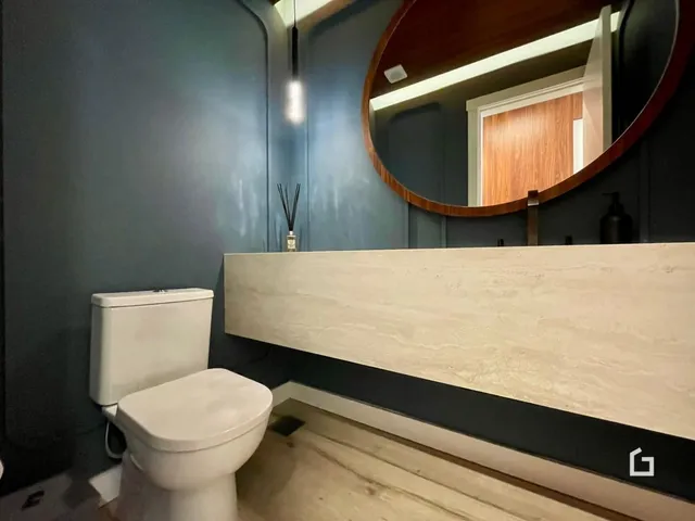Foto de um banheiro com vaso sanitário e bancada de madeira clara.