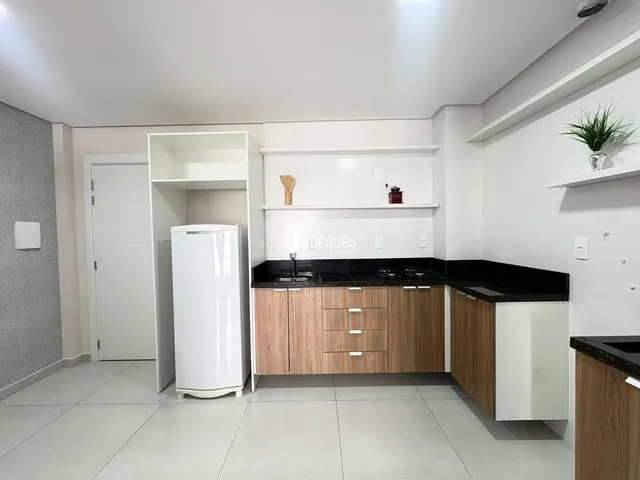 Vista da cozinha moderna com armários de madeira e bancadas escuras.