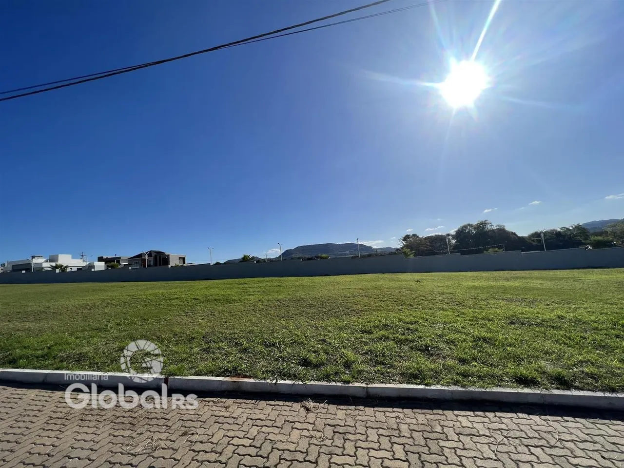 Vista externa de um gramado com muro ao fundo.