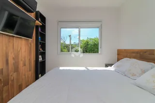 Quarto com cama e janela em ambiente claro.