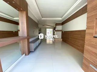 Foto de um ambiente interno longo com revestimento de madeira e piso claro.