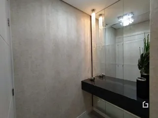 Vista de um corredor com parede clara e espelho refletindo o ambiente.