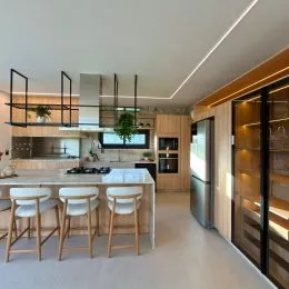 Cozinha moderna com bancada e banquetas em ambiente interno.