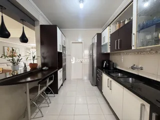 Vista interna de uma cozinha com armários escuros e piso claro.