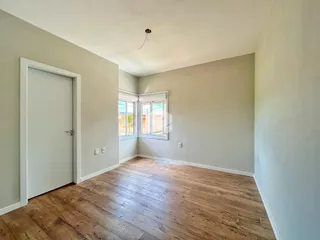 Vista interna de um ambiente com piso de madeira e porta branca.