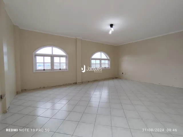 Ambiente interno de uma sala com piso de cerâmica e duas janelas arqueadas.